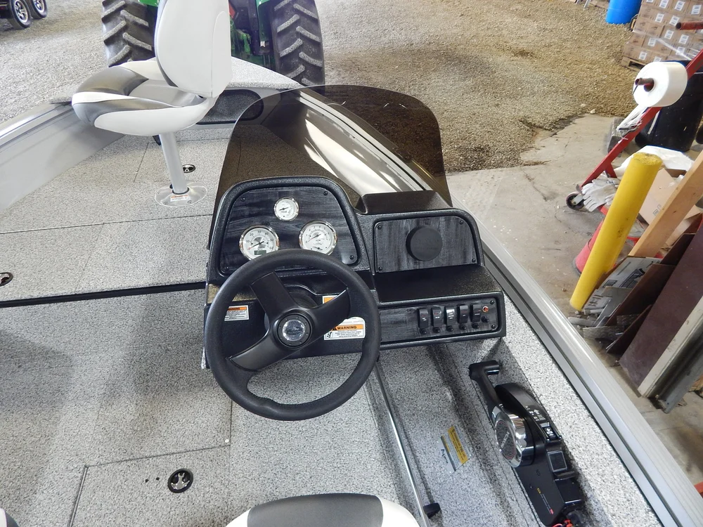 Boat cockpit interior featuring steering wheel, control panel with gauges, and seating, showcasing detailed craftsmanship and hardware quality for prospective buyers at Mike and Dave's Pro Marine.