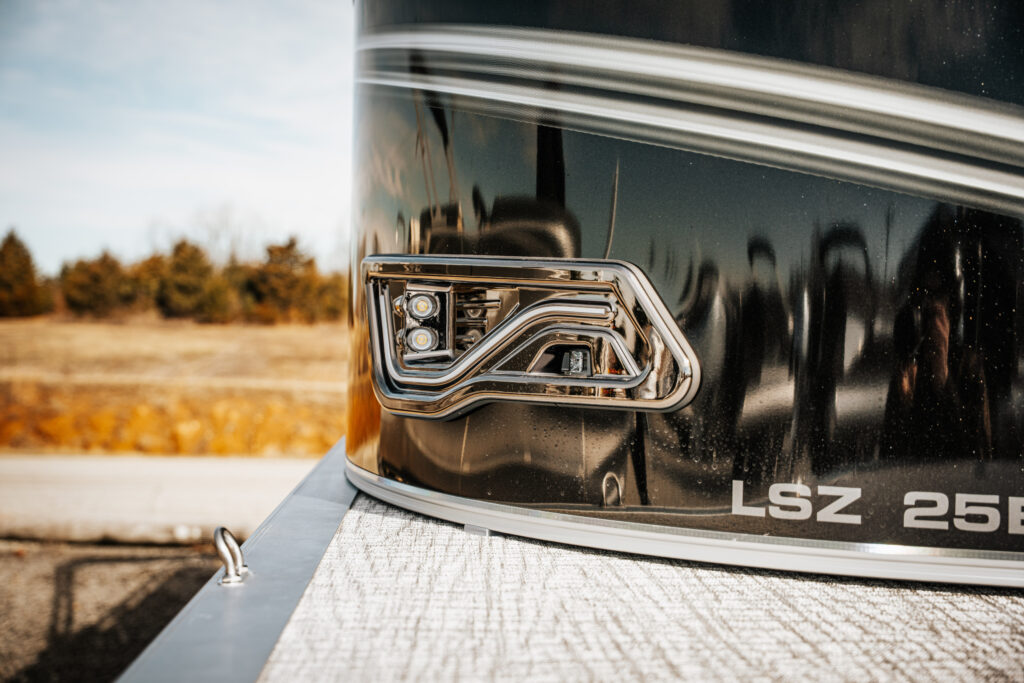 Detail of the 2026 Avalon LSZ boat featuring LED smoked chrome docklights and polished corner caps, showcasing the sleek flat black and gloss black finish.