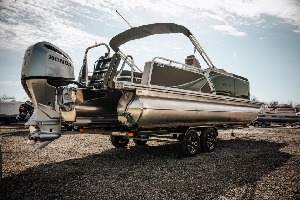 2026 Avalon LSZ boat in flat black and gloss black with Honda motor, showcasing versatile rear bench and trailer, set against a clear sky.