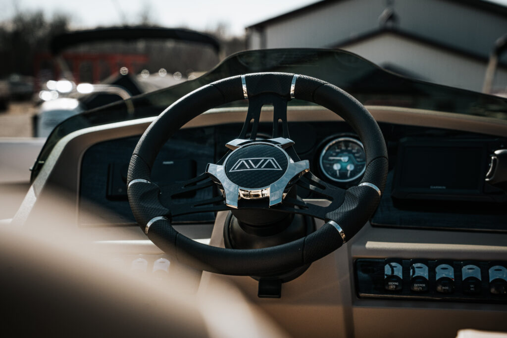 Steering wheel of the 2026 Avalon LSZ boat featuring the Avalon logo, with dashboard controls and gauges in the background.