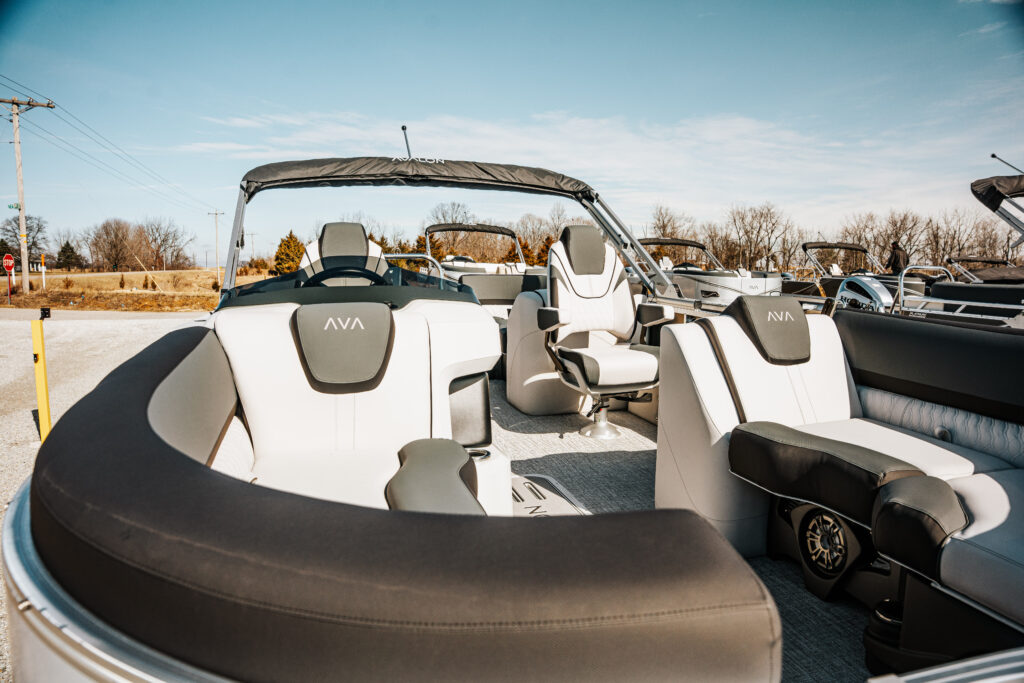 2026 Avalon LSZ boat interior showcasing white and grey seating, including Sport High Back Reclining Chair, with a view of the steering wheel and surrounding features, set against a clear blue sky.