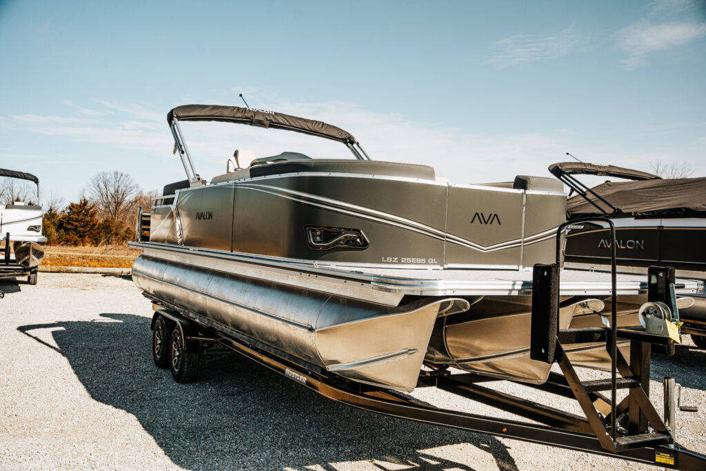 Avalon LSZ boat in charcoal color with silver accents, parked on a trailer in a marine lot, showcasing sleek design and modern features.