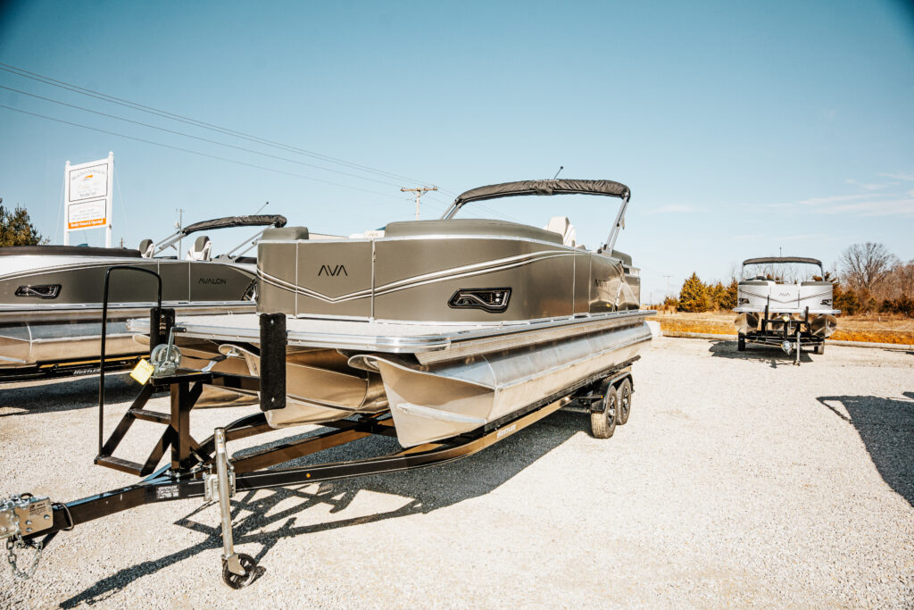 2026 Avalon Catalina Quad Lounger in Matte Black on trailer, showcasing sleek design and premium features, with additional boats visible in the background.