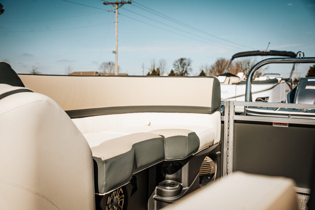 Avalon Catalina Quad Lounger interior seating in matte black and cream vinyl, showcasing plush cushions and stylish design, with boats in the background.