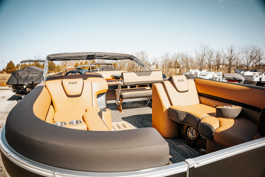 2026 Avalon LSZ boat interior featuring plush seating with gold and black accents, including high back reclining chairs and sleek design elements, showcased in a marina setting.