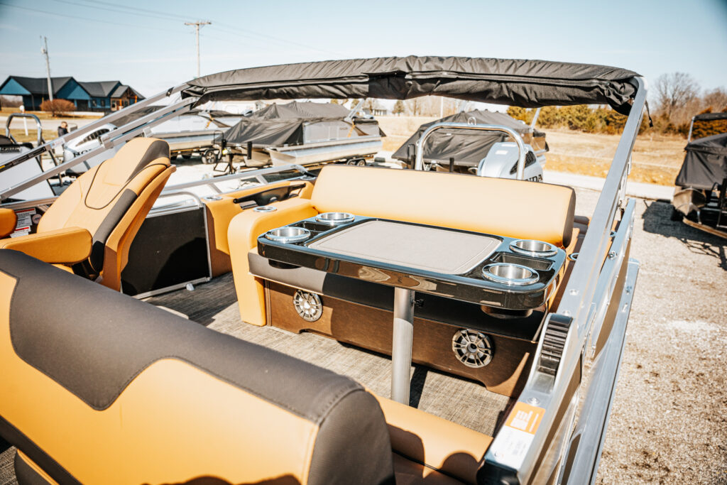 2026 Avalon LSZ boat interior featuring black and cream seating, sport high back reclining chair, integrated table with cup holders, and polished chrome accents.