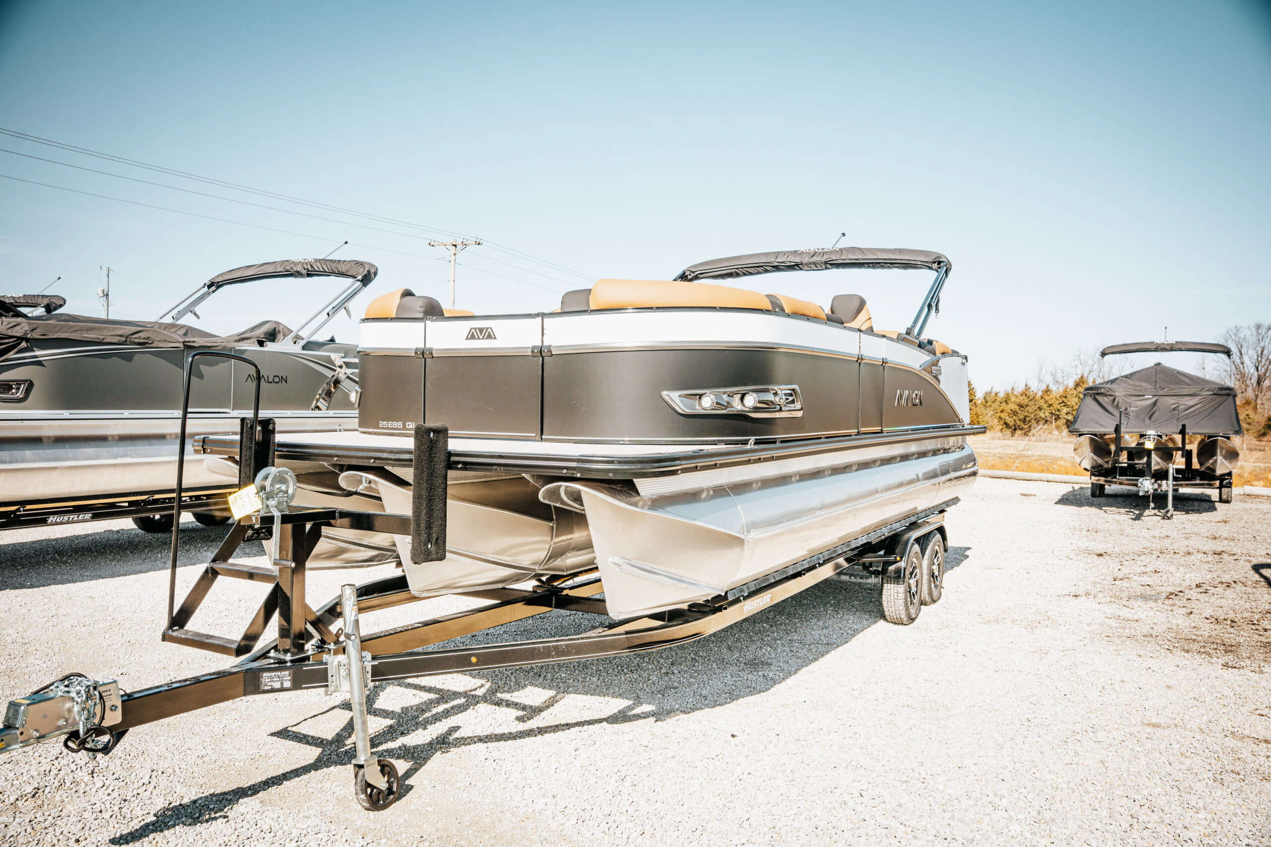 2026 Avalon LSZ boat in black and white, featuring a sleek design, plush seating, and mounted on a trailer, showcased in a marina setting.