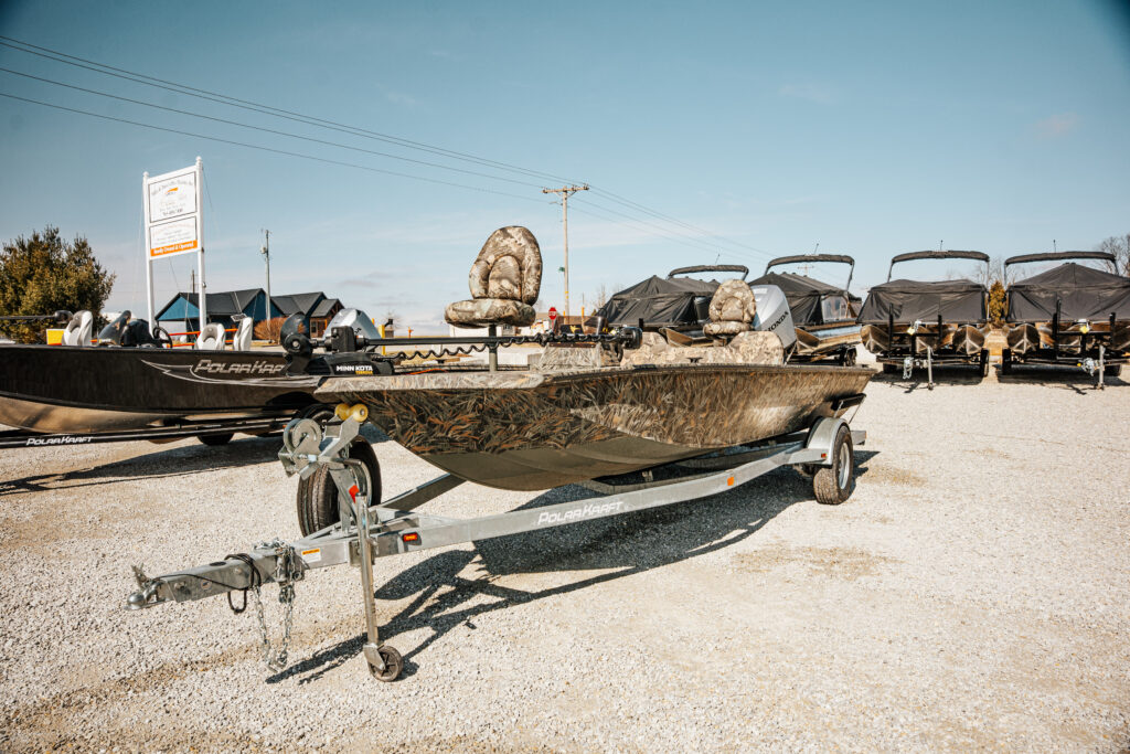 2024 Polar Kraft Frontier 165 SC fishing boat on trailer, featuring upgraded seats, mooring cover, and surrounded by additional boats at Mike & Dave's Pro Marine.