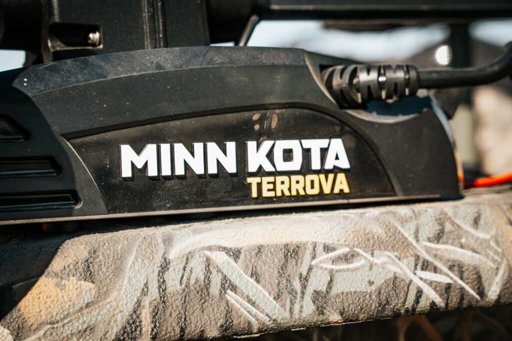 Minn Kota Terrova trolling motor control unit on a camouflage boat surface, highlighting fishing features of the 2024 Polar Kraft Sport X 190 SC.