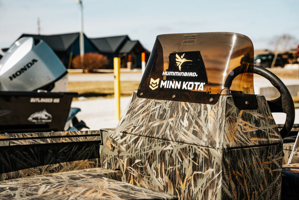 Fishing boat seat featuring Humminbird and Minn Kota logos, with a Honda motor visible in the background, showcasing the 2024 Polar Kraft Sport X 190 SC's upgraded fishing features.