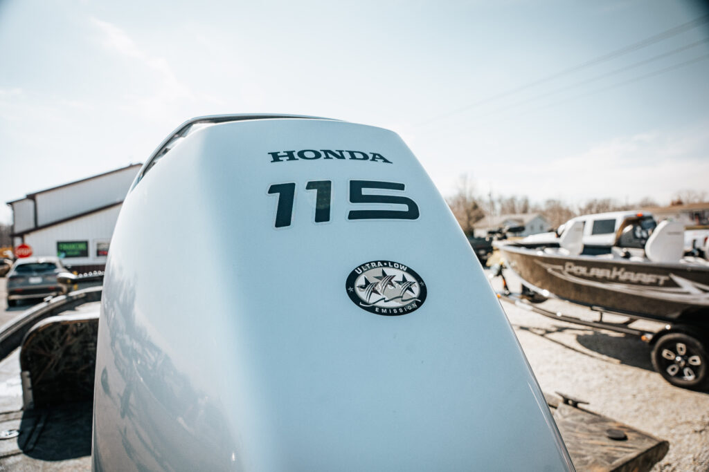 Honda 115 HP motor with ultra-low emissions, featured on the 2024 Polar Kraft Sport X 190 SC boat, showcasing marine setting and nearby boats.