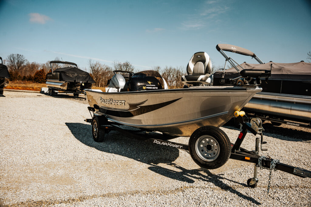 2024 Polar Kraft Frontier 165 SC boat with 90 HP Honda motor, showcasing upgraded fishing seats and trailer, parked on gravel lot.