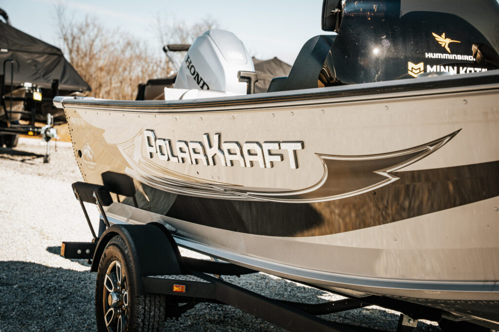 Polar Kraft boat with visible branding and Honda motor, showcasing features in a gravel setting, related to the 2024 Polar Kraft Frontier 165 SC model.