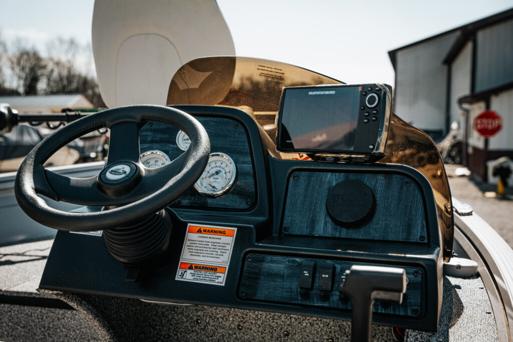 Boat dashboard featuring steering wheel, gauges, and Humminbird fish finder, highlighting the 2024 Polar Kraft Frontier 165 SC's control features and technology.