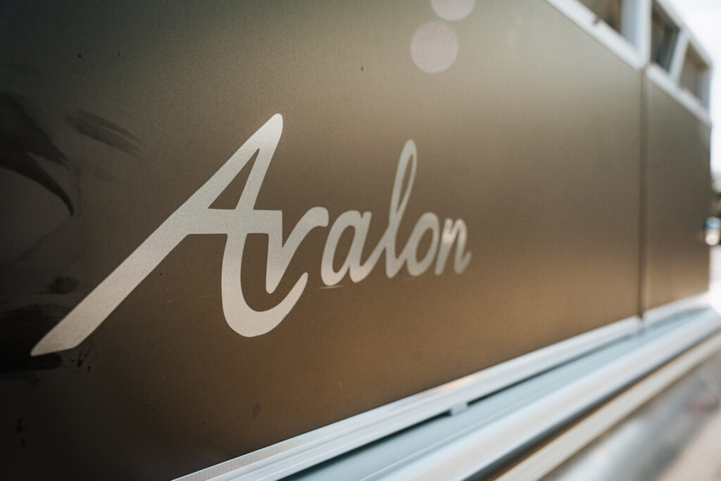 Avalon logo on the side of a 2024 Avalon Venture Quad Lounger boat, highlighting the brand associated with luxury marine products.