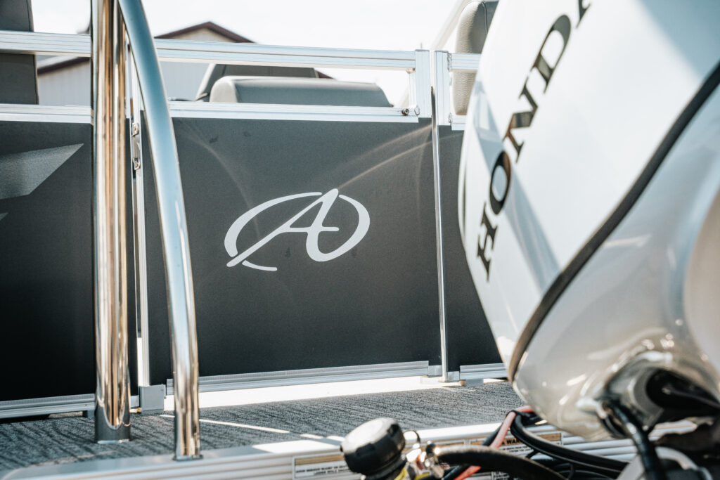 Avalon logo on the side of a 2024 Avalon Venture Quad Lounger boat, featuring a Honda motor and sleek design elements.