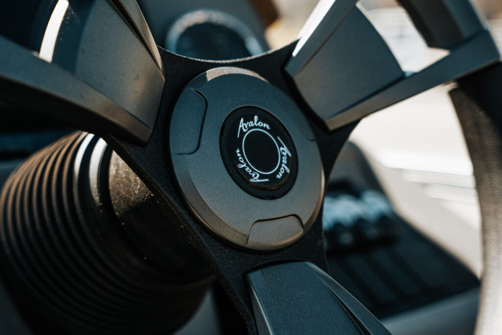 Avalon steering wheel with logo, showcasing modern design and control features in a boat interior setting.