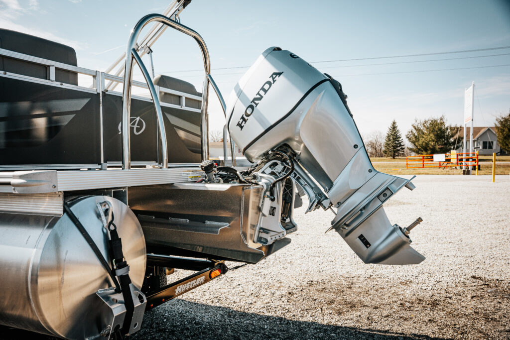 2024 Avalon Venture Quad Lounger with Honda 90 HP motor, showcasing sleek design and Hustler trailer in outdoor setting.