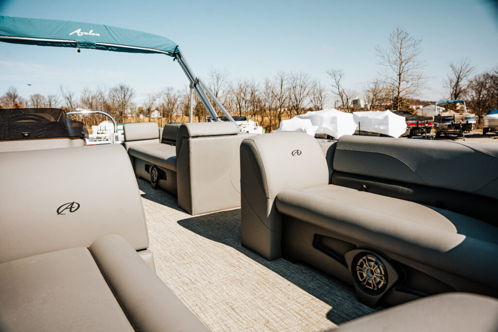 Interior view of the 2024 Avalon Venture Quad Lounger boat featuring gray seating, Avalon logo, and a canopy, showcasing spacious seating for 10 and stylish design elements.