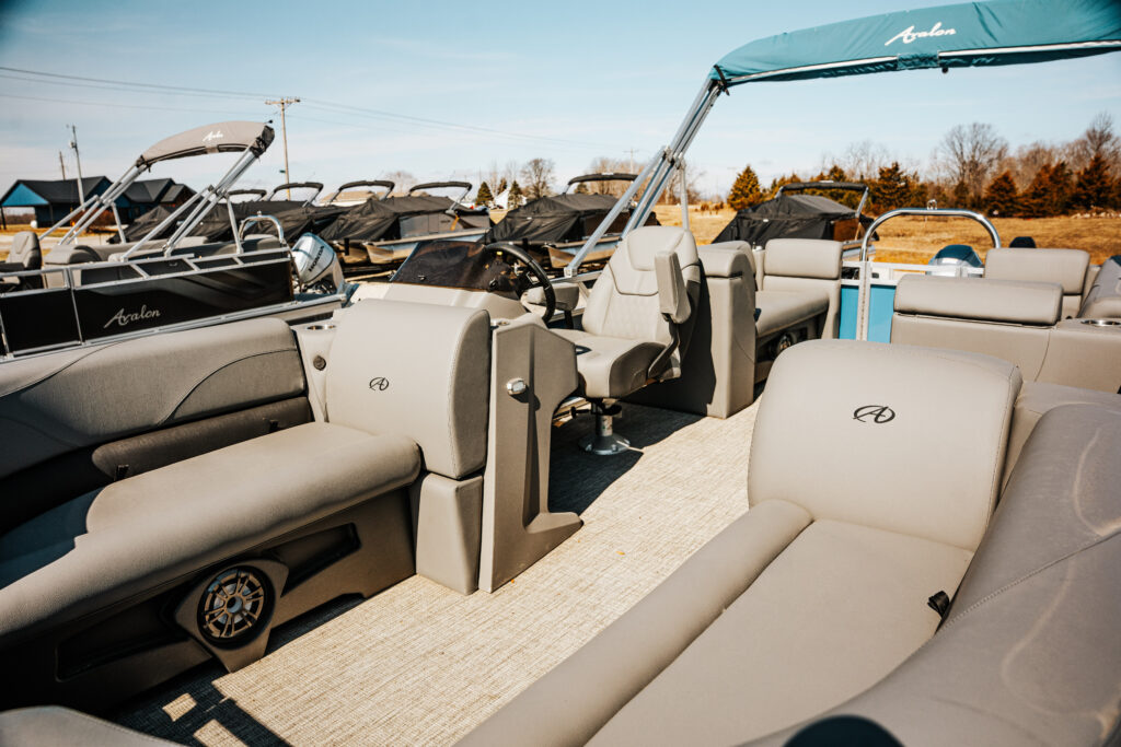 Interior view of the 2024 Avalon Venture Quad Lounger (Blue) showcasing gray seating, steering console, and spacious layout designed for comfort and leisure on the water.