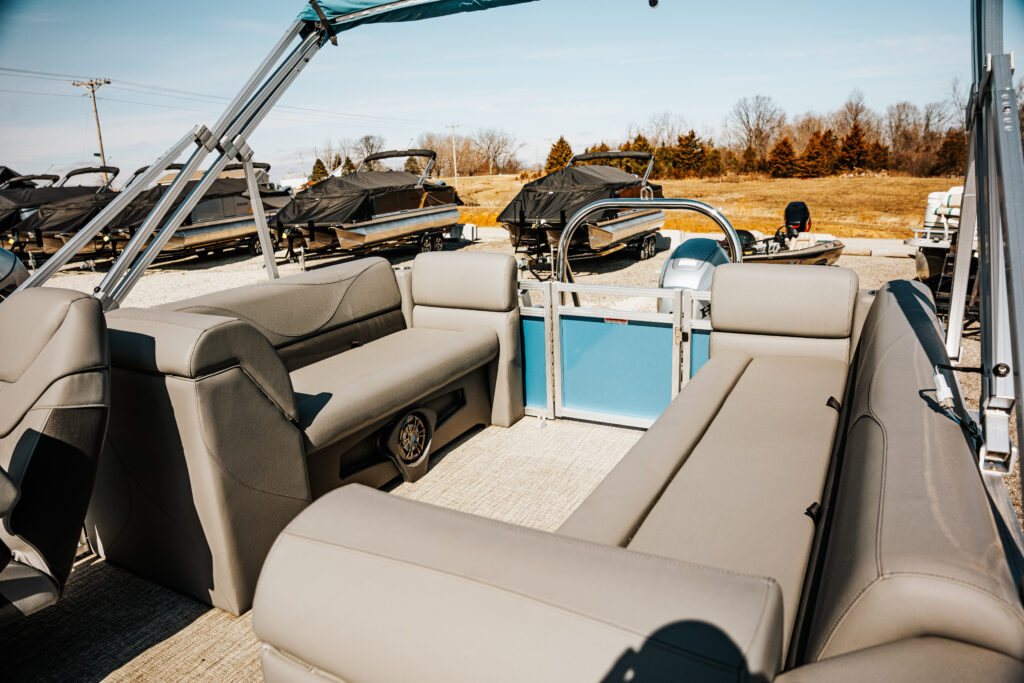Interior view of the 2024 Avalon Venture Quad Lounger (Blue) showcasing spacious seating with charcoal vinyl upholstery, designed to accommodate up to 10 people, set against a backdrop of other boats.