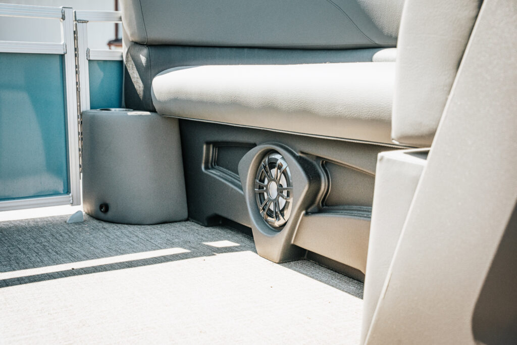 Interior view of the 2024 Avalon Venture Quad Lounger showcasing seating, a built-in speaker, and stylish gray upholstery, emphasizing comfort and entertainment features for boaters.