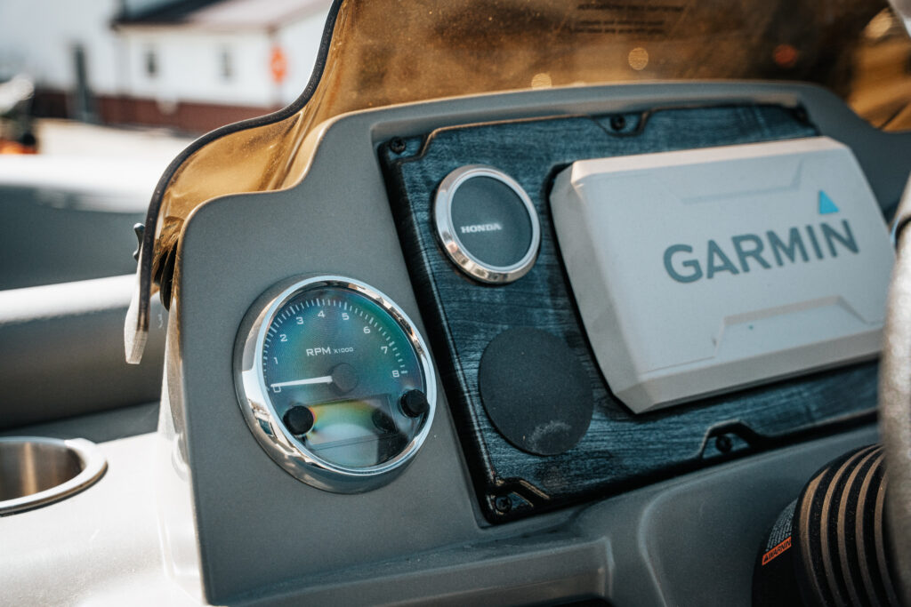 Garmin display and RPM gauge on the dashboard of the 2024 Avalon Venture Quad Lounger boat, showcasing Honda motor controls and sleek design features.